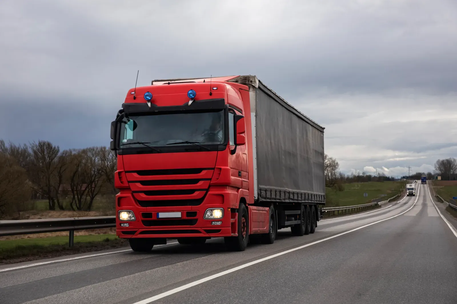 Lorries on a dual carriageway beside a logistics park, overlaid with live fleet-tracking graphics.