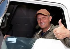 A smiling driver giving a thumbs-up from a lorry cab